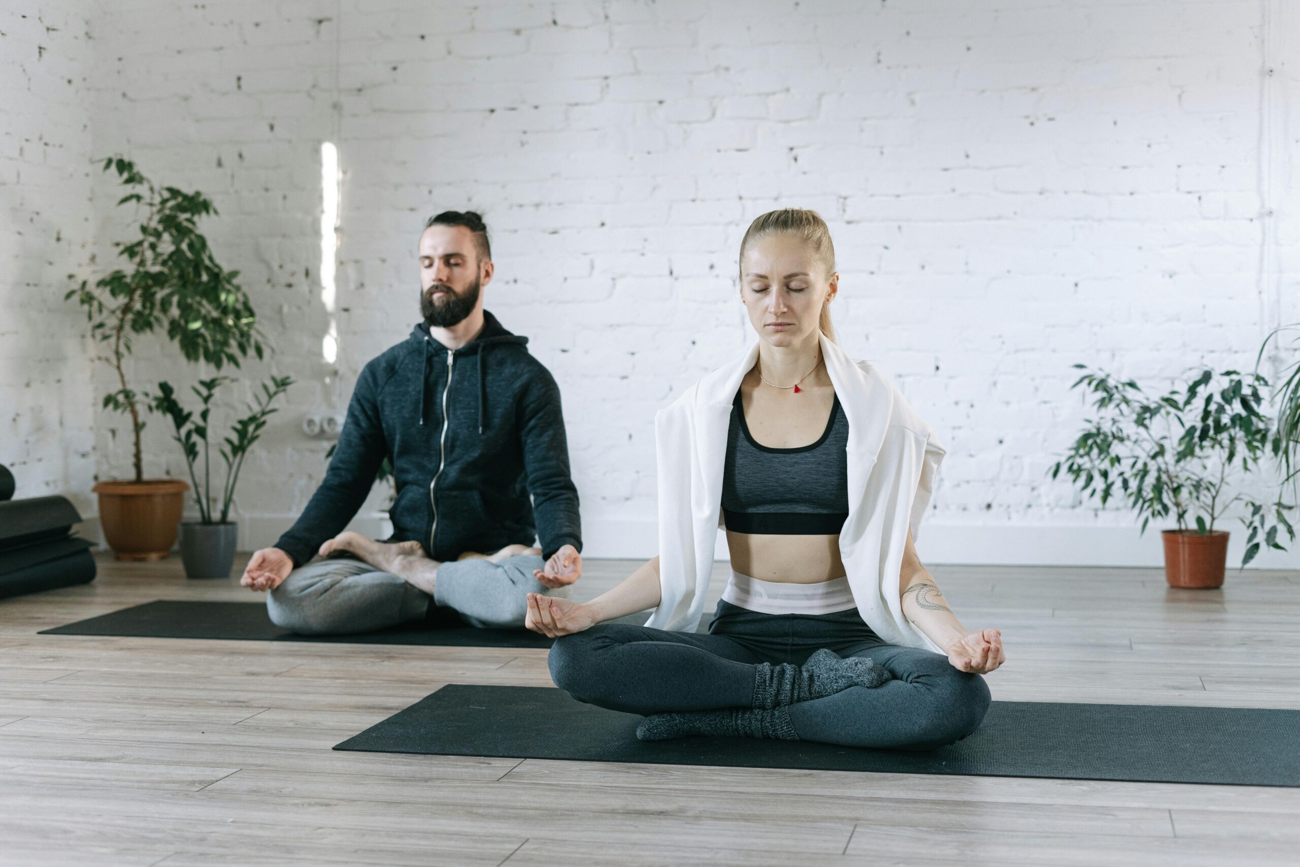 A man and woman meditate in a serene indoor space, promoting mindfulness and wellness.